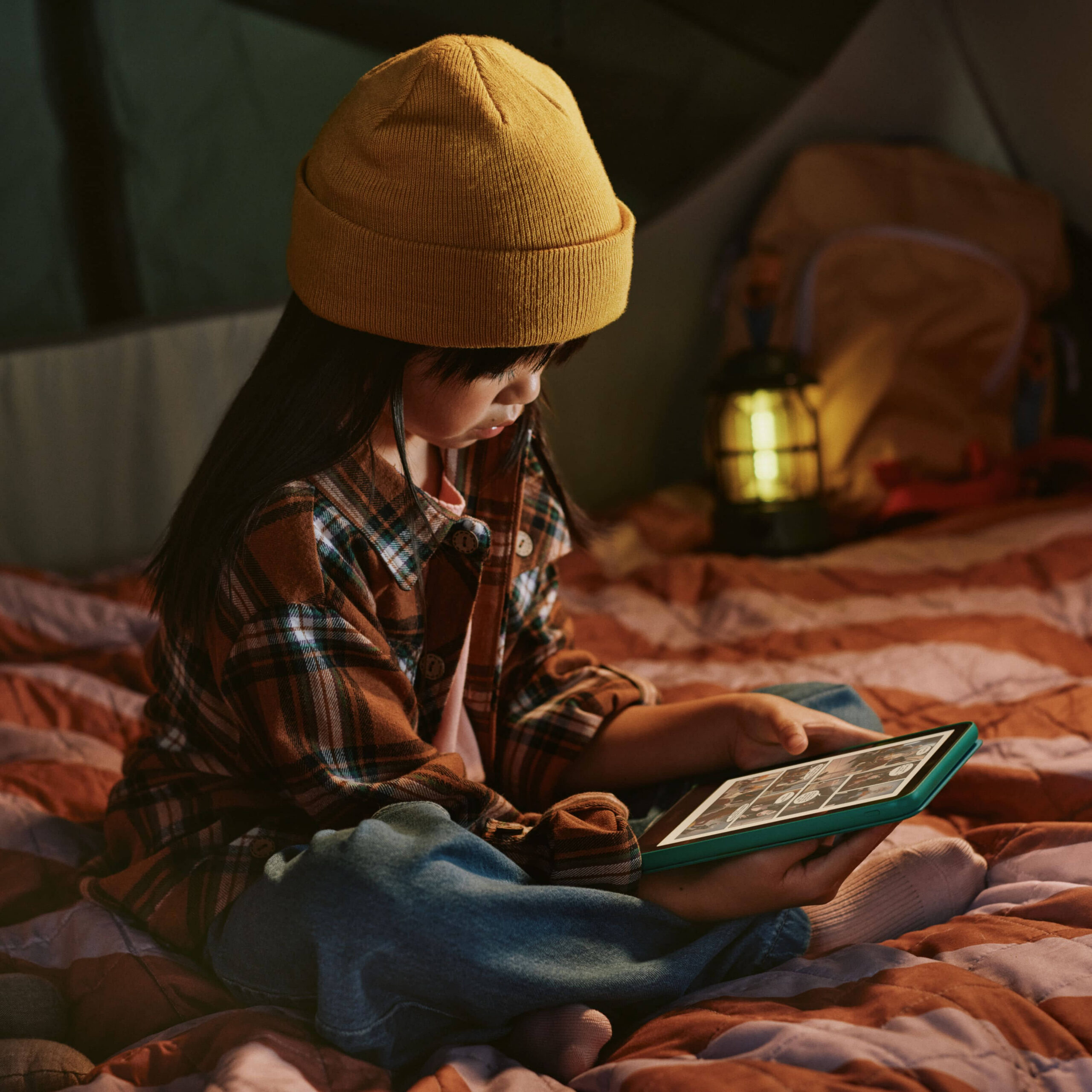 A young reader enjoying a book on Kindle in a cosy room